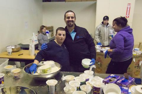 SRC employee and a food bank volunteer filling plastic containers with food