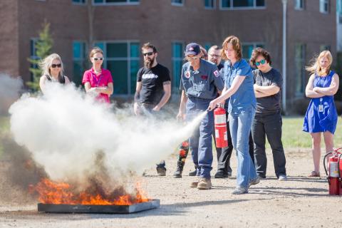 Woman using fire extinguisher on a controlled burn during training