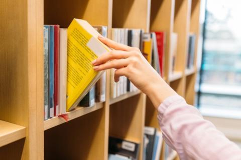 woman taking src recommended leadership book off shelf